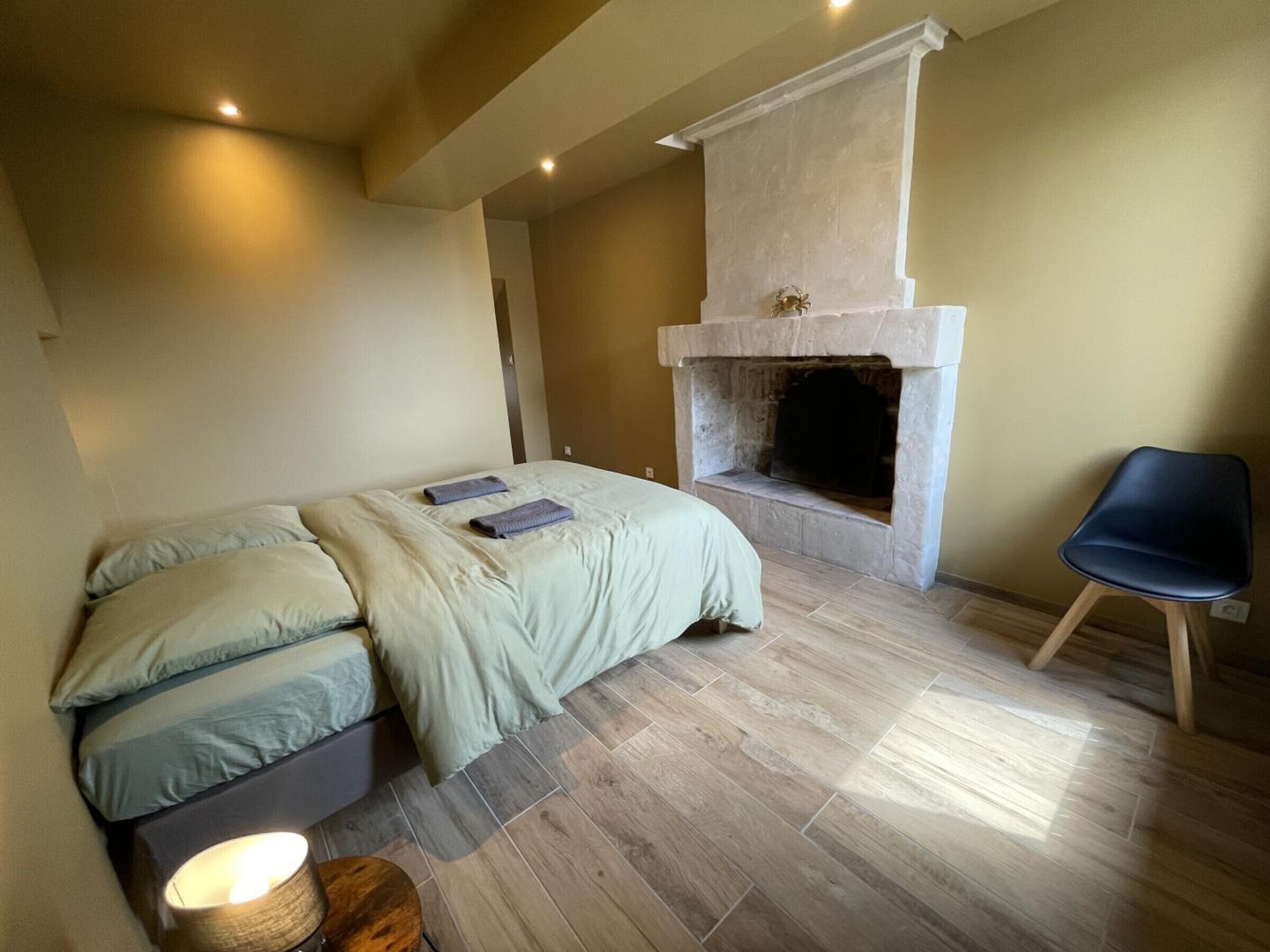 Una camera da letto con un letto, una sedia, un caminetto e un comodino.