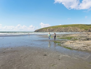 A beach with rocky terrain and a grassy hill in the background. - Hafod Grove - UKC6955 (Moylegrove, near Ceibwr Bay)