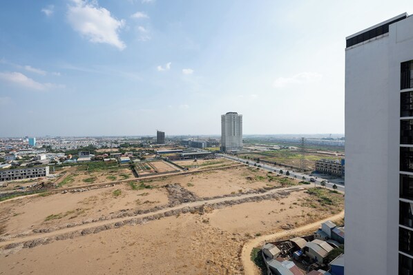 A high-rise building with a view of a cityscape, including a large building and a highway.