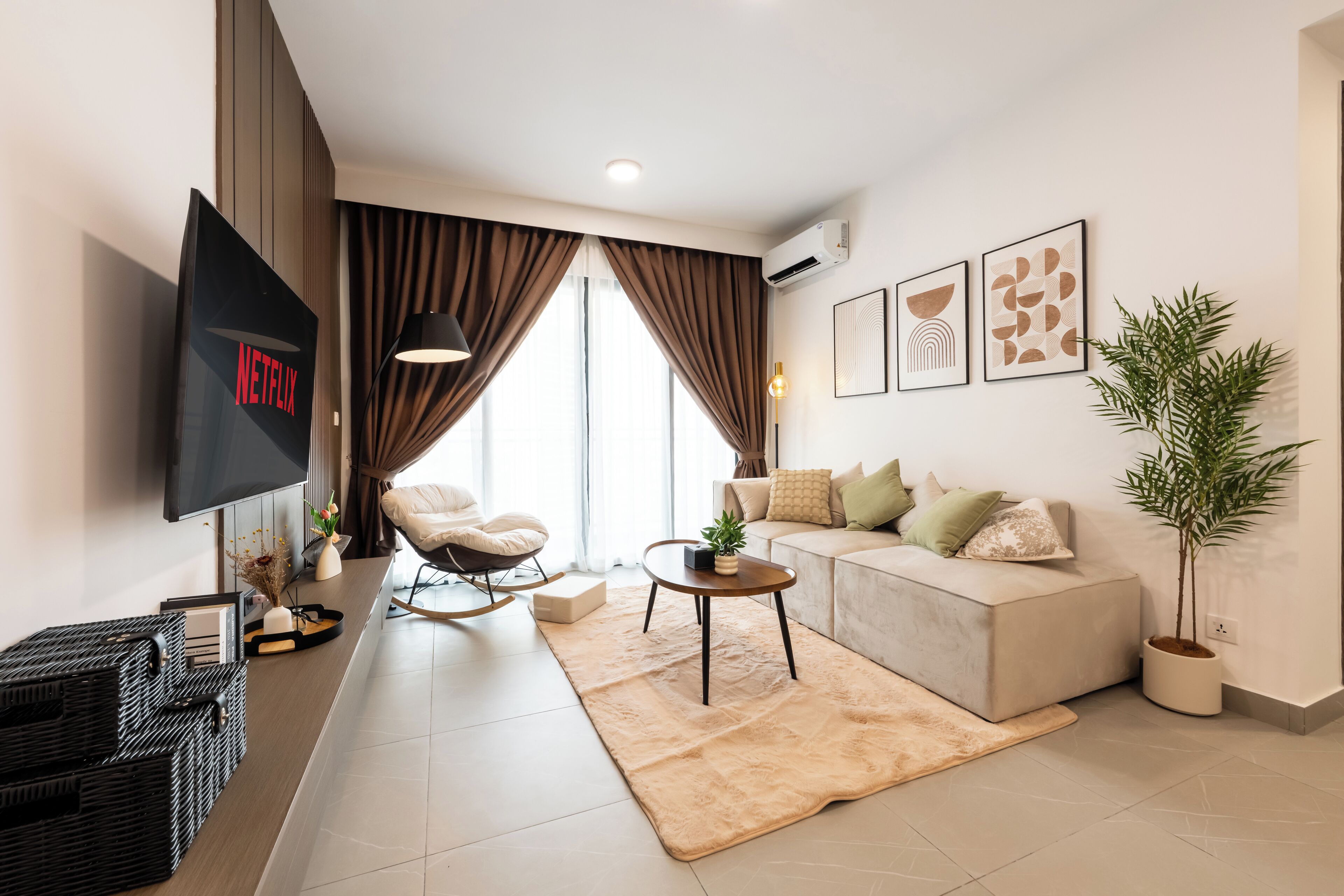 A modern living room with a flat-screen TV, a sofa, a coffee table, and a large window with curtains.
