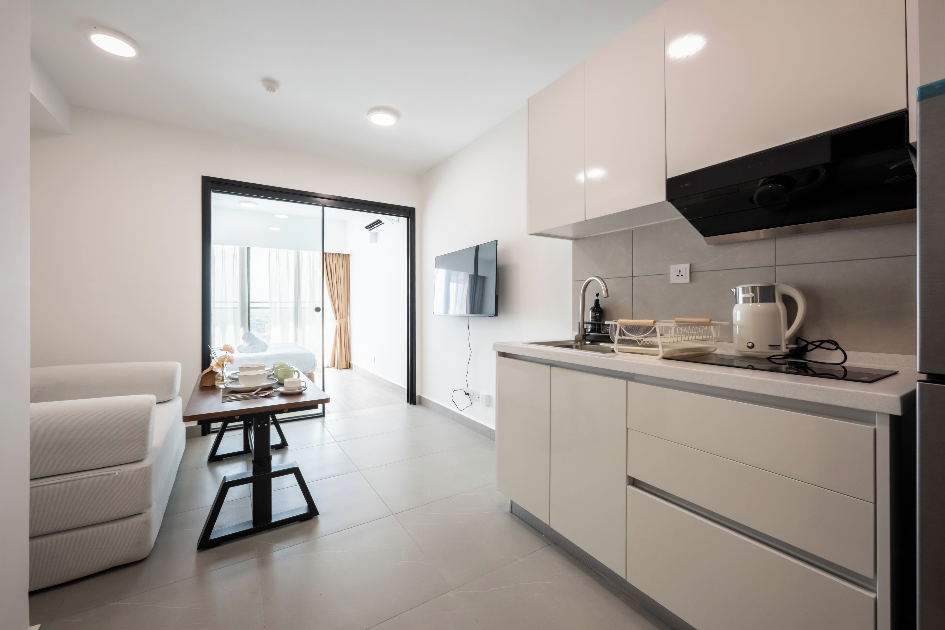 A modern kitchen with white cabinets, a built-in oven, and a coffee maker.
