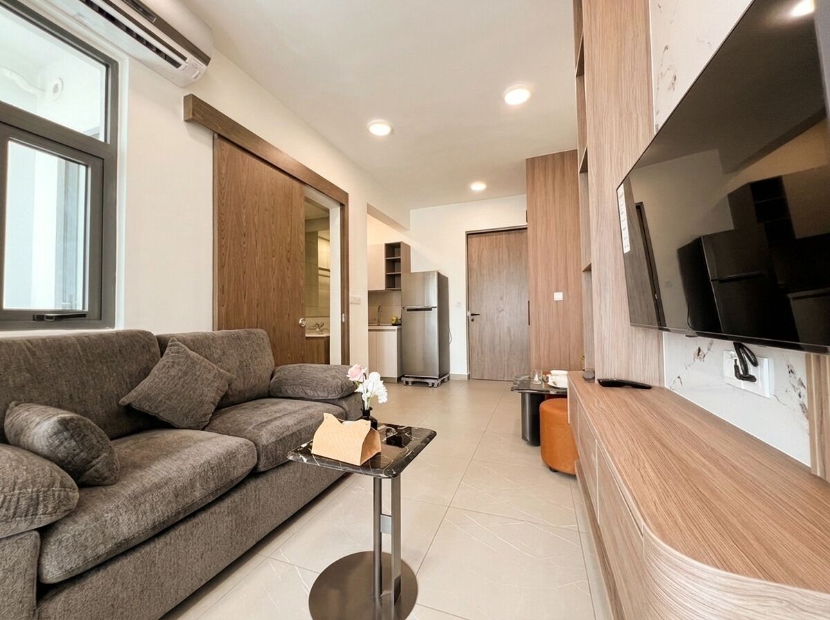 Een moderne woonkamer met een bank, een salontafel en een flatscreen televisie aan de muur.