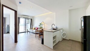 Una cocina moderna con lavadora integrada, un comedor con mesa y sillas, y un ventanal que proporciona luz natural.
