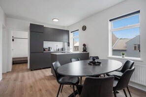 Una cocina moderna con armarios oscuros, una isla central y un comedor con mesa redonda y sillas.