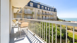 A balcony with a white railing, a chair, and a table.