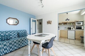 A compact living space with a sofa, a dining table, and a kitchenette. - Cap Sur L’océan – Beautiful Sea View (Pornic)