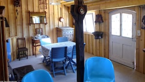 A rustic wooden room with a dining table, blue chairs, a wooden cabinet, and hanging birdcages. - Charming Studio with Garden and Terraces, Peaceful and Historic Setting (Mersuay)
