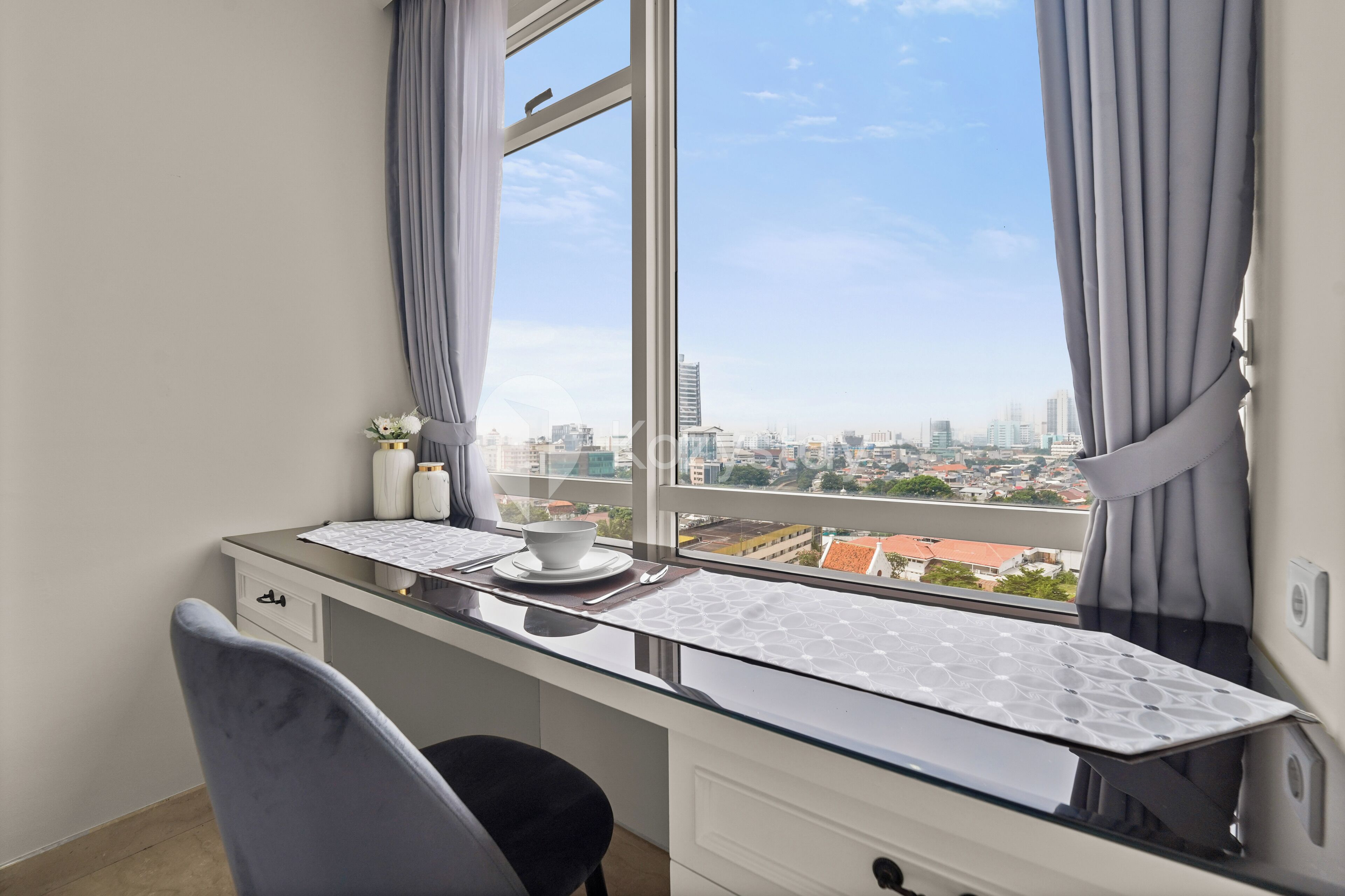 Una camera da letto moderna con vista sulla città, una scrivania con tazza e piattino e una sedia.