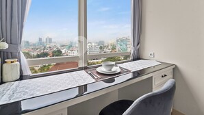 A modern room with a city view, a desk with a bowl and cutlery, and a chair. - Halden by Kozystay - Menteng (Jakarta)