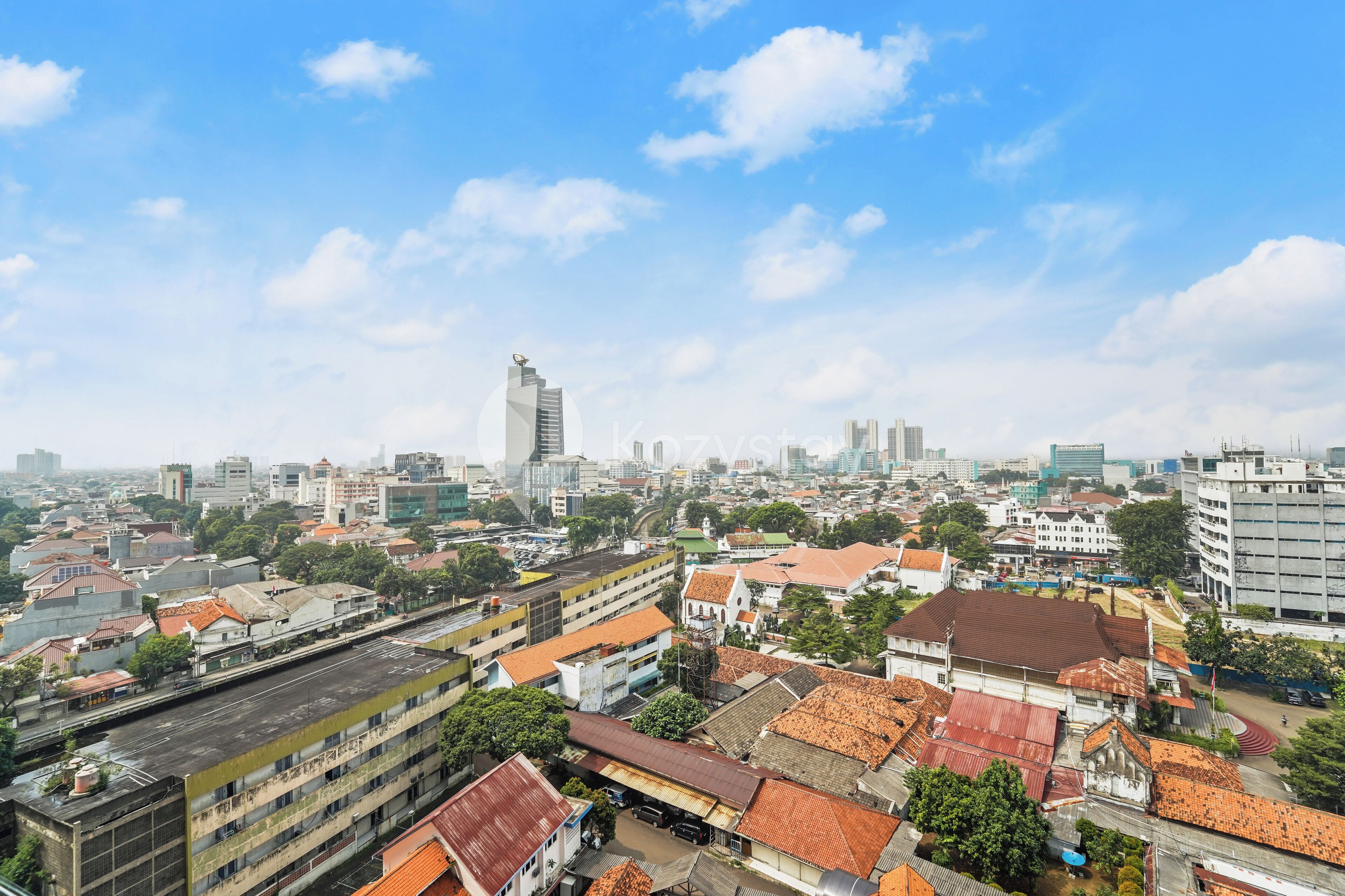 A cityscape with a mix of modern and traditional buildings, a prominent skyscraper, and a clear blue sky.
