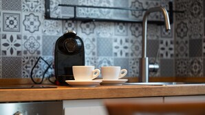Et køkken med kaffemaskine, to kopper og en vask.