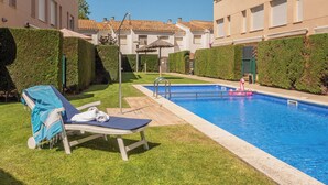 A swimming pool with lounge chairs, a small inflatable flamingo, and neatly trimmed hedges. - Charming triplex with jacuzzi in Calonge (Calonge)