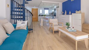 A modern living room with a blue sofa, wooden coffee table, and a staircase with blue railings. - Charming triplex with jacuzzi in Calonge (Calonge)