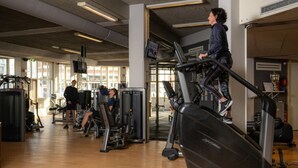 Een sportschool met loopbanden, gewichtstoestellen en een grote spiegel.