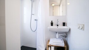 Een moderne badkamer met een douche, wastafel en spiegel.