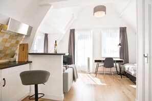 A compact, modern apartment with a kitchenette, a dining area, and a bedroom. - Penthouse apartment near Scheveningen beach (Den Haag)