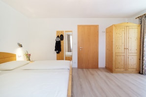A bedroom with a bed, a wardrobe, a mirror, and a door. - Apartment 'Schupfe' with Mountain View, Shared Garden and Wi-Fi (Ratschings)