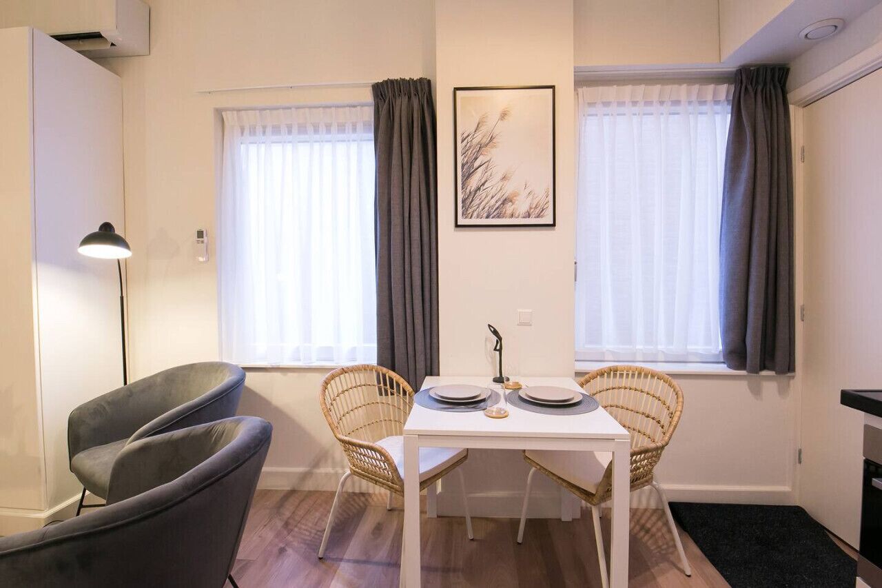 En matplats med ett vitt bord, två fåtöljer i rotting och en grå soffa.