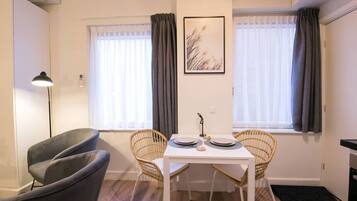 En matplats med ett vitt bord, två fåtöljer i rotting och en grå soffa.