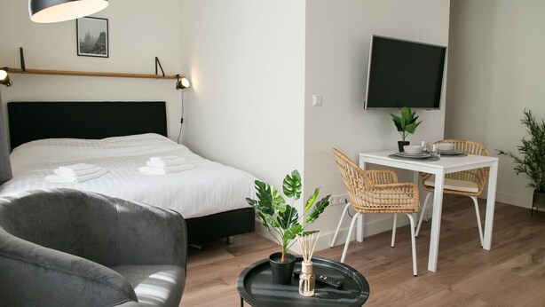 Ett sovrum med en säng, ett nattduksbord, en lampa och en liten matplats med ett bord och stolar.