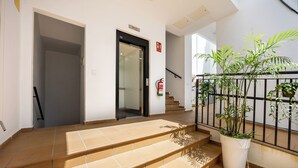 Una escalera que conduce a un piso superior, un extintor de incendios sujeto a la pared y una planta en maceta a la derecha.