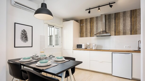 Una cocina moderna con armarios blancos, una campana extractora de acero inoxidable y un microondas.
