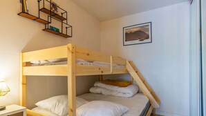 A bunk bed with a desk and shelves, a framed picture on the wall, and a patterned rug.