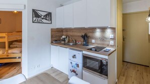 A compact kitchen with white cabinets, a wooden countertop, a built-in oven, and a refrigerator.
