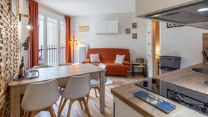 A compact living space with a dining area, kitchenette, and a cozy orange sofa.