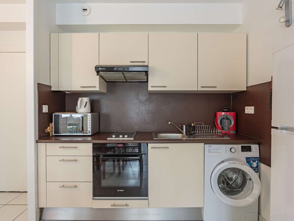 Una cocina compacta con horno Bosch, lavadora y cafetera.