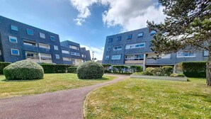 A modern apartment complex with a paved pathway, neatly trimmed hedges, and a clear sky. - Ground floor apartment near sea, sleeps 4 (Bernières-sur-Mer)