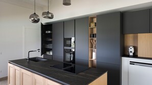 Una cocina moderna con encimera negra, electrodomésticos integrados y armarios de madera.
