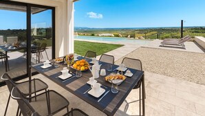 Un área de comedor al aire libre con vistas a una piscina y al paisaje.