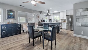 A modern kitchen with a central island, stainless steel appliances, and a ceiling fan. - Spacious 3BR, 2BA beach home just a short walk from the sand! Three bedrooms up, private queen room and bath down. Secure 2-car garage for vehicles or a small boat. Perfect for families or groups. 30-day minimum stay required. (New Smyrna Beach)