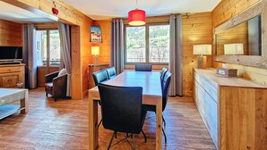 A wooden cabin with a dining area, a TV, and a large window with a view of the outdoors. - La Clusaz - Apartment 6 ppl, 53 sqm, 2 bedrooms, WiFi (La Clusaz)