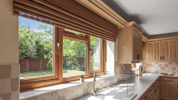 Una cocina con un ventanal amplio, armarios de madera y salpicadero de azulejos.