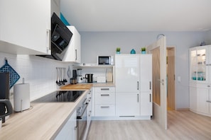 Eine moderne Küche mit weißen Schränken, einer Mikrowelle, einem Toaster und einer Holzausziehtafel.