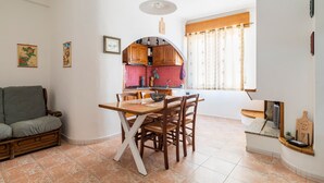 A dining area with a wooden table and chairs, a sofa, and a kitchen in the background.