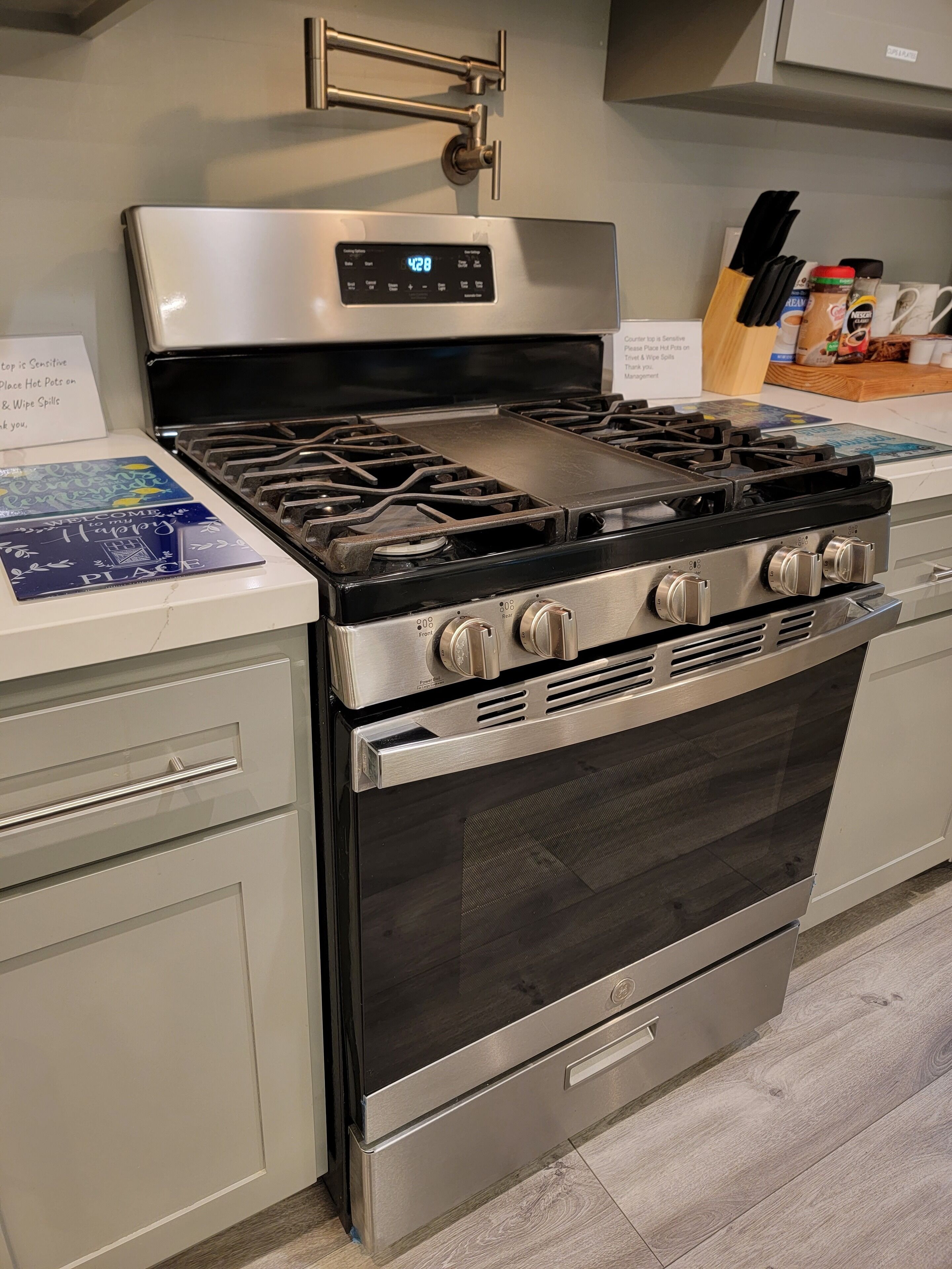 Une cuisinière à gaz en acier inoxydable, dotée de quatre brûleurs, d’une horloge numérique et d’un four en acier inoxydable situé en dessous.