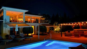 A two-story building with a pool, outdoor seating, and string lights.