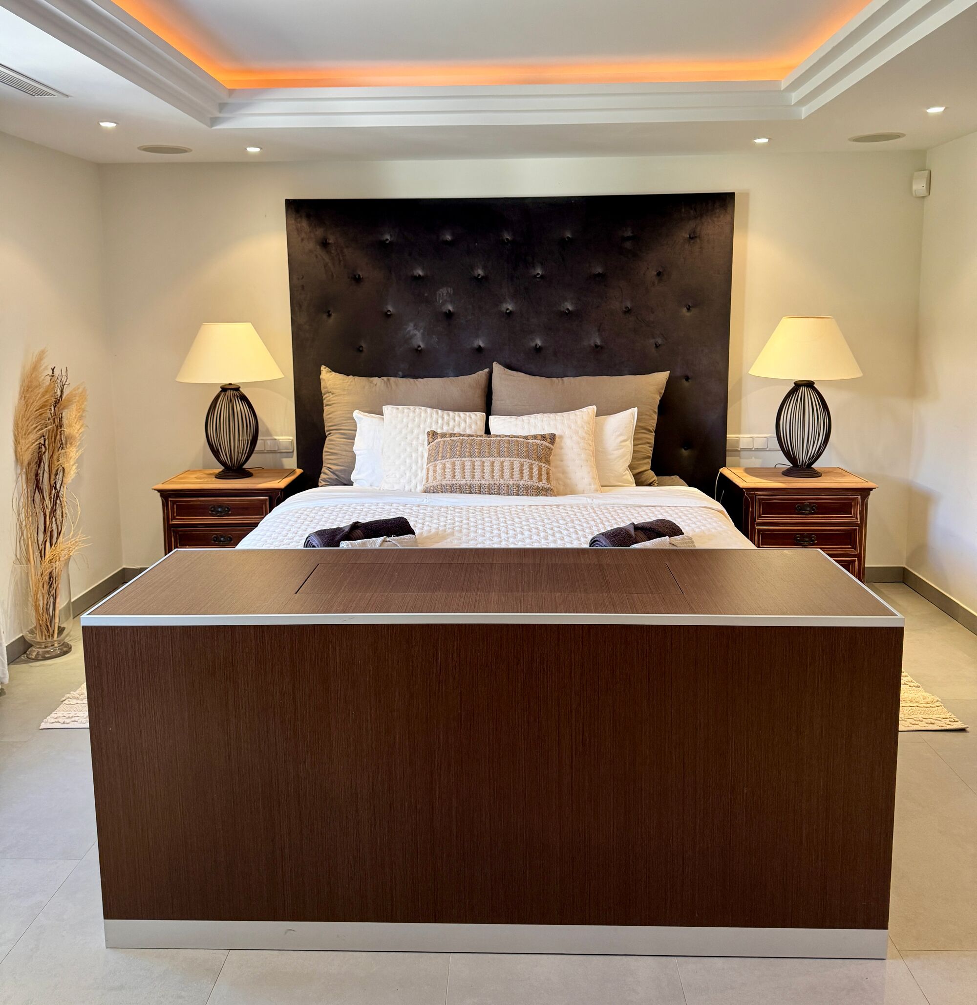 A modern bedroom with a large bed, two bedside tables, and a nightstand.