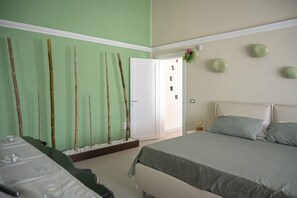 A room with a bed, a massage table, and a wall with vertical bamboo sticks.