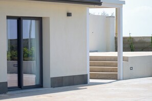 A modern building with a glass door entrance, a concrete staircase, and a flat roof.