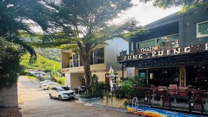 A Thai restaurant named "Thai Food Running Pueng" with outdoor seating and a decorative welcome sign. - Cozy Apartment GM8 (Koh Samui)