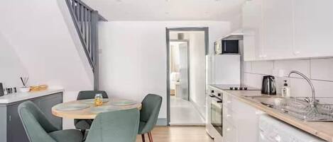 Una cocina moderna con comedor, lavadora y una escalera.