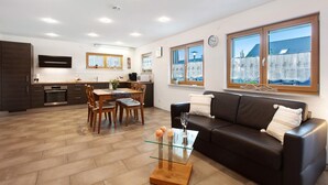 Una sala moderna con una mesa de centro de vidrio, un sofá de cuero y un comedor con sillas de madera.