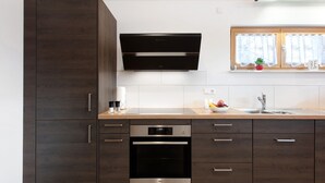 Una cocina moderna con armarios de madera oscura, horno de acero inoxidable y microondas integrado.