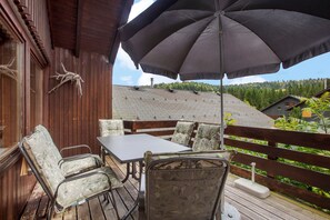 A wooden deck with outdoor furniture, a table, and an umbrella.
