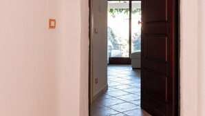 A hallway with a wooden door, a small house-shaped decoration, and a colorful doormat. - Casa di Barbara al Mare by Wonderful Italy (Olbia)