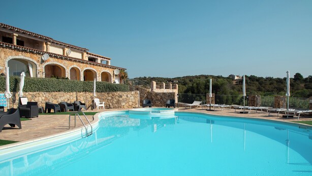 A swimming pool with lounge chairs and umbrellas, a stone building with arches, and a view of a hillside. - Casa di Barbara al Mare by Wonderful Italy (Olbia)